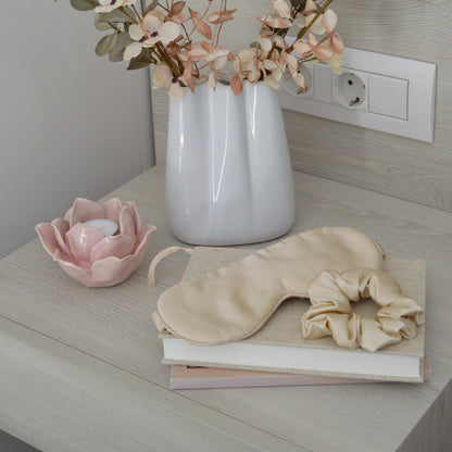 Champagne silk hair scrunchie and silk sleep mask in a bedroom interior