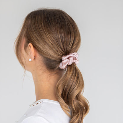 Model wearing an extra glossy pink 3 cm wide silk scrunchie in brown hair viewed from the side