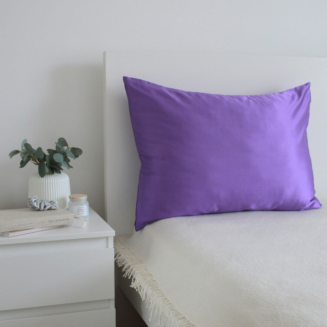 Lilac premium mulberry silk pillowcase,  and silver hair scrunchies in a bedroom interior