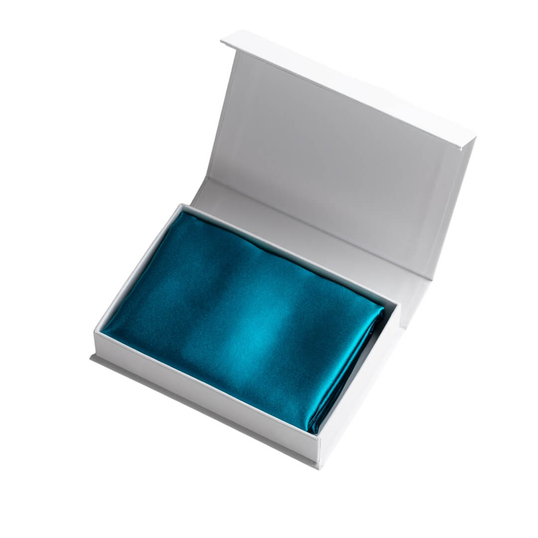 Turquoise silk pillowcase in an open white gift box with silver branding