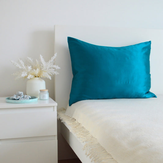 Turquoise premium mulberry silk pillowcase in a cozy bedroom interior