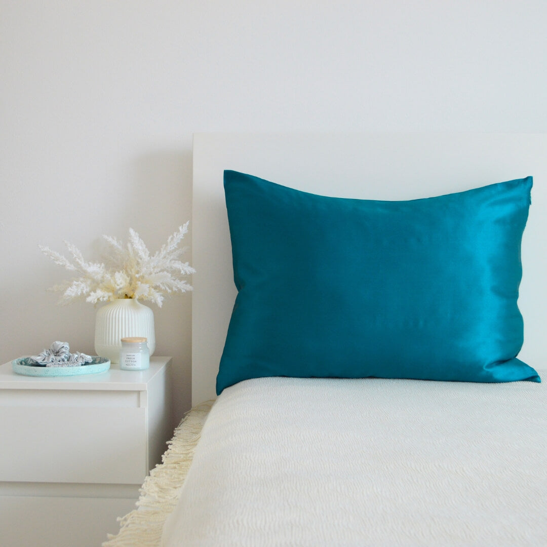 Turquoise premium mulberry silk pillowcase in a cozy bedroom interior