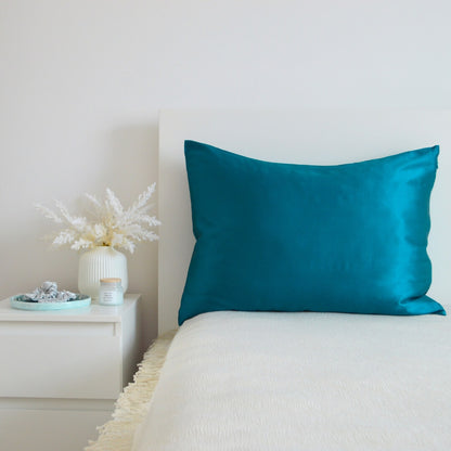 Turquoise premium mulberry silk pillowcase in a cozy bedroom interior